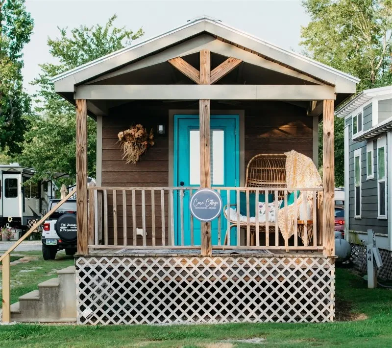 A small wooden cottage with a covered porch and a blue door